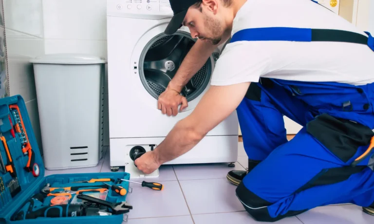 a person in overalls repairing a washing machine.